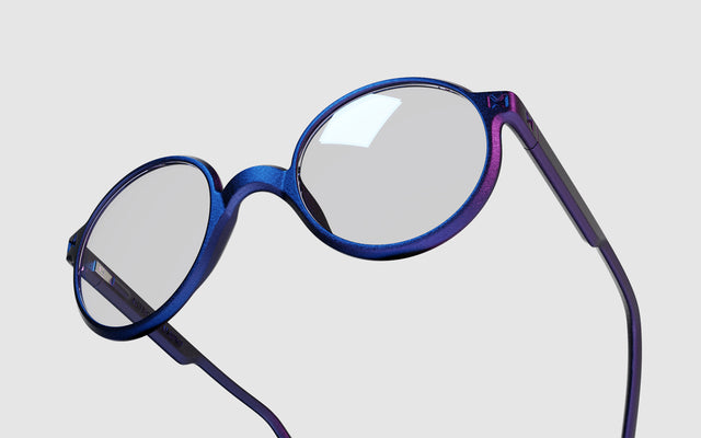 Close-up view of REFRAMD blue light glasses with round, iridescent frames showcasing a stylish gradient effect.