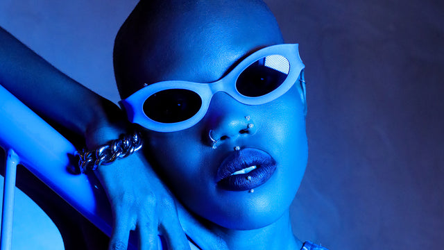 Model posing in futuristic style with Cosmic Oracle oval sunglasses, blue lighting