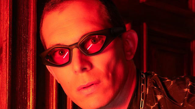 Male model wearing black REFRAMD sunglasses in red lighting, part of the Afronaut Collection, capturing a futuristic and bold look