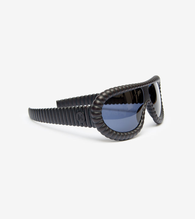 Sleek side view of matte black sunglasses with blue reflective lenses and distinctive coiled arm design, showcased against a stark white background for a modern and stylish appearance